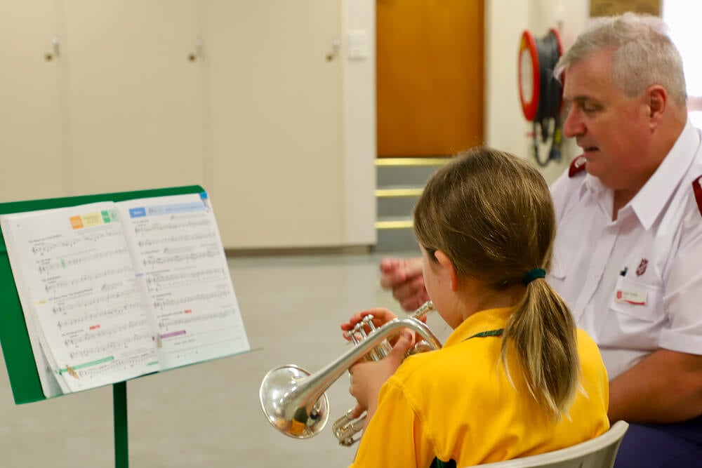 Child and Salvos Officer playing brass instruments. Just Brass offers free music lessons to children in parts of Australia and beyond