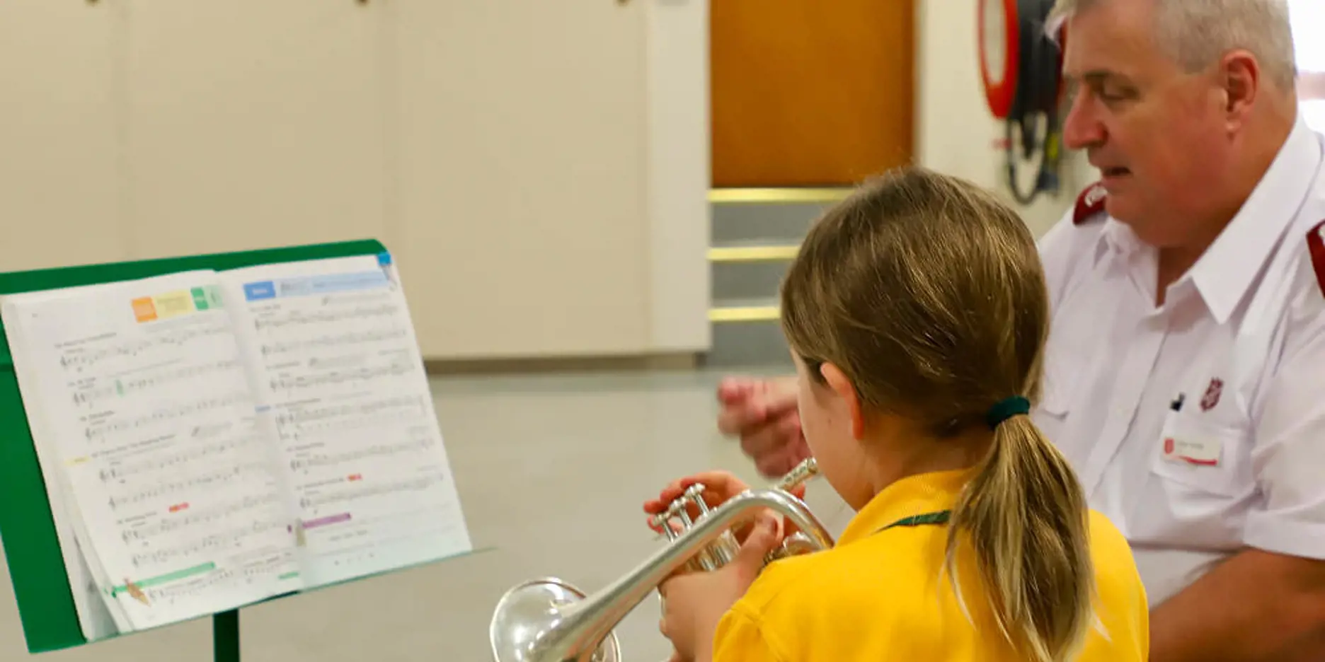 Child and Salvos Officer playing brass instruments. Just Brass offers free music lessons to children in parts of Australia and beyond