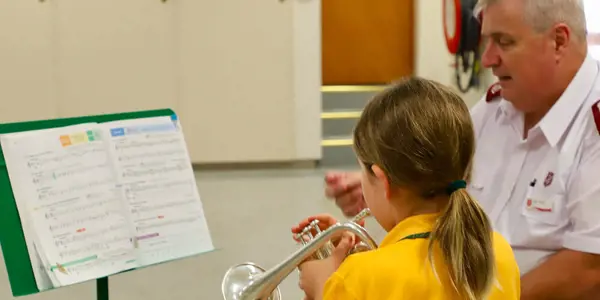 Child and Salvos Officer playing brass instruments. Just Brass offers free music lessons to children in parts of Australia and beyond