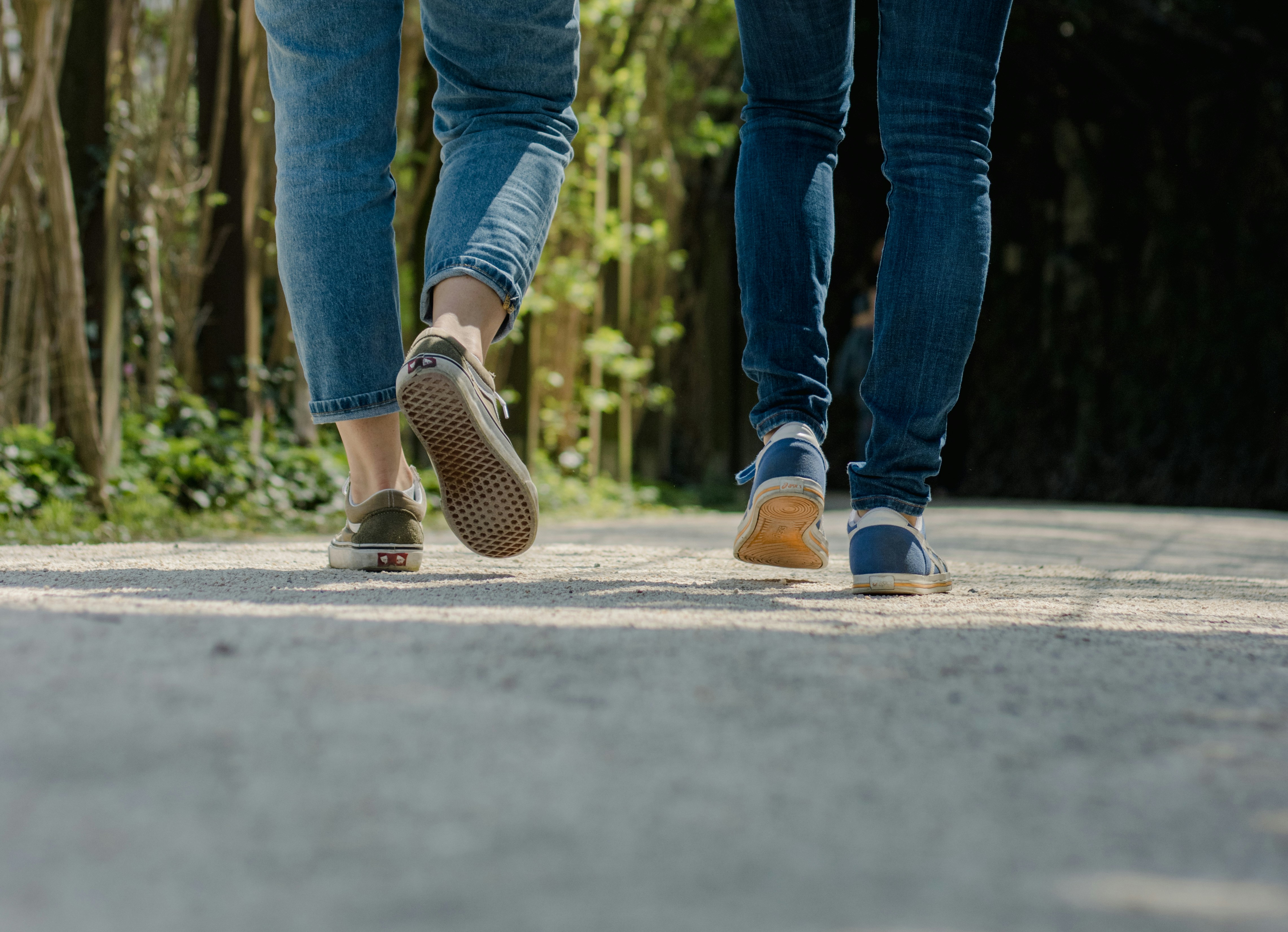 Two people's legs as they walk down the street. 