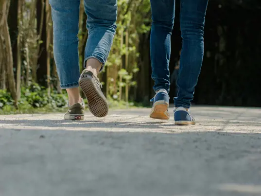 Two people's legs as they walk down the street.