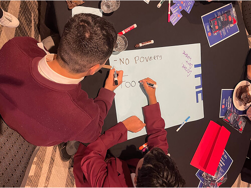 High school students working together writing on a piece of paper