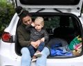 A mother and child sitting on boot of car