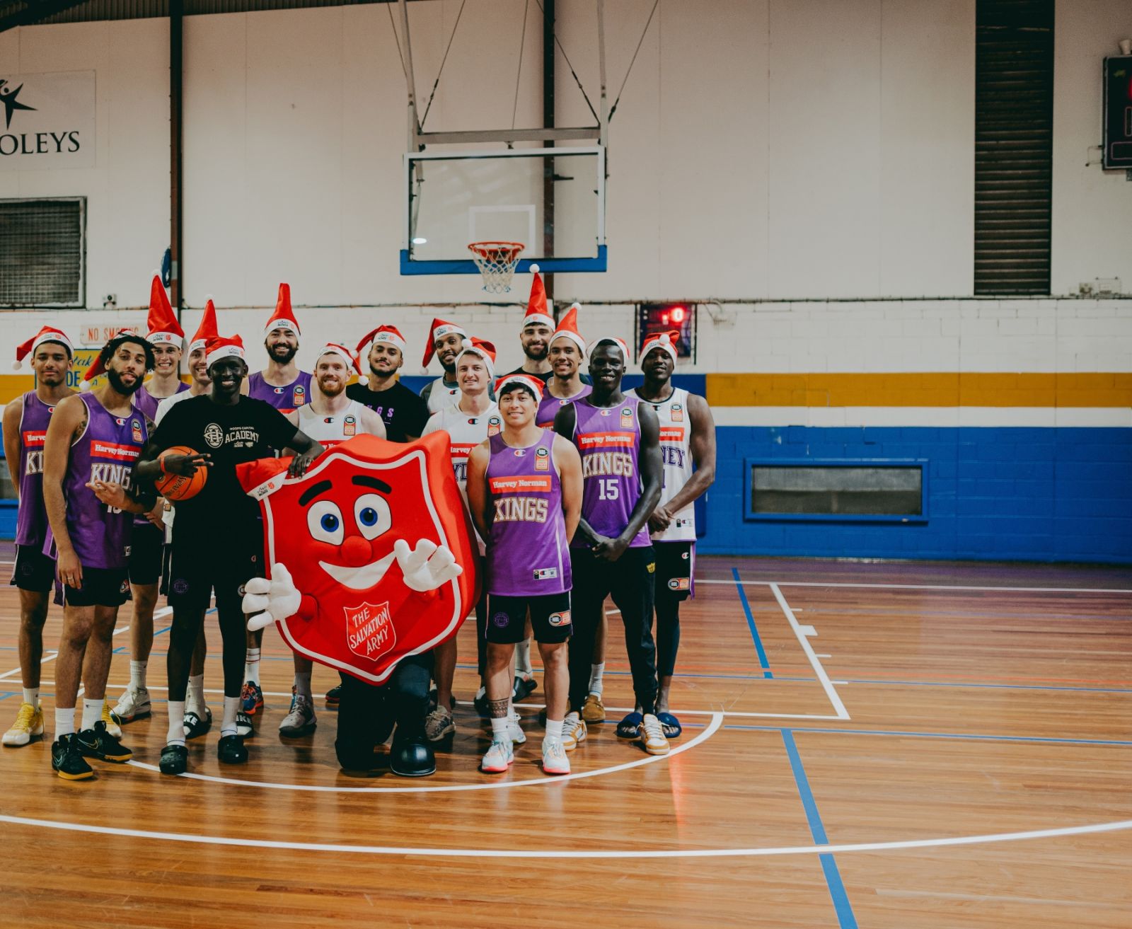 Sydney Kings players posing with Shieldy the Salvos mascot