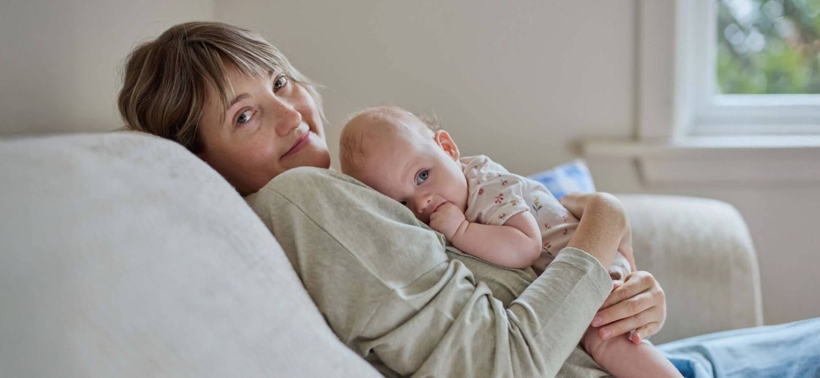 Mother holding baby while sitting on a couch.