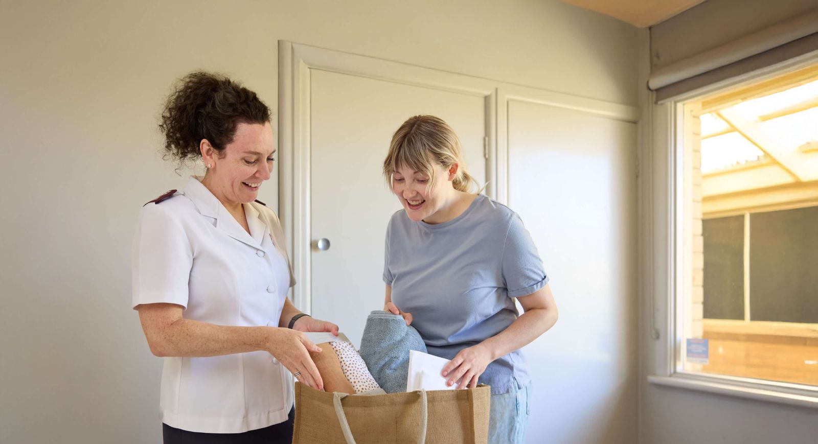 Salvos personnel handing a hamper filled with groceries to a mother in need