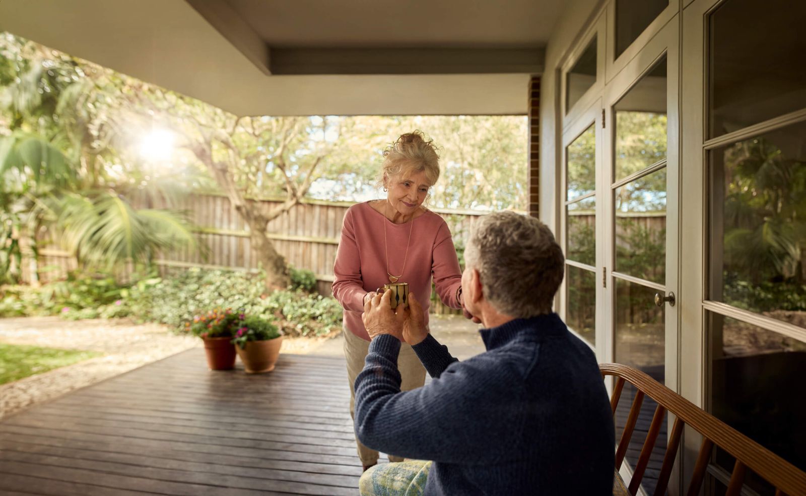 Elderly couple standing in the patio of their house laughing.