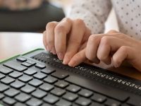 person reading braille on a computer keyboard