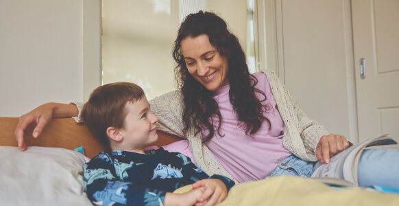 Suzi smiling with her son, sitting on a couch of her home.