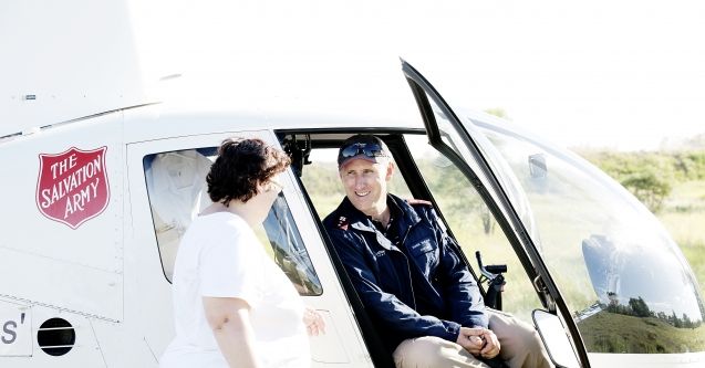 A Salvation Army helicopter pilot has a conversation with a woman.