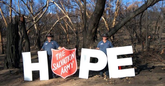Chaplain with Hope sign after a bush fire