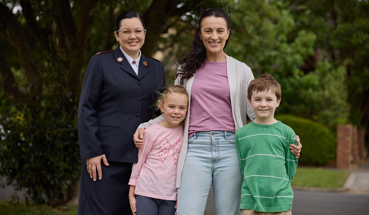Suzi with her two children, smiling with a Salvos personnel