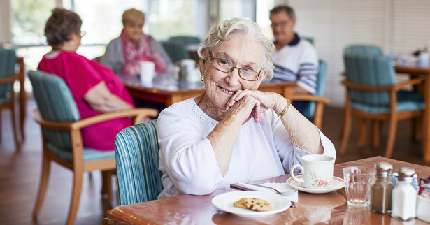 Senior smiling over a cup of tea and a biscuit