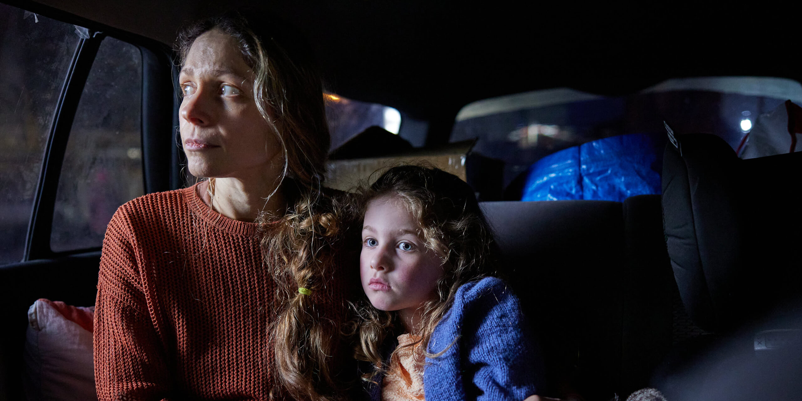 Woman and child sheltering in a car.