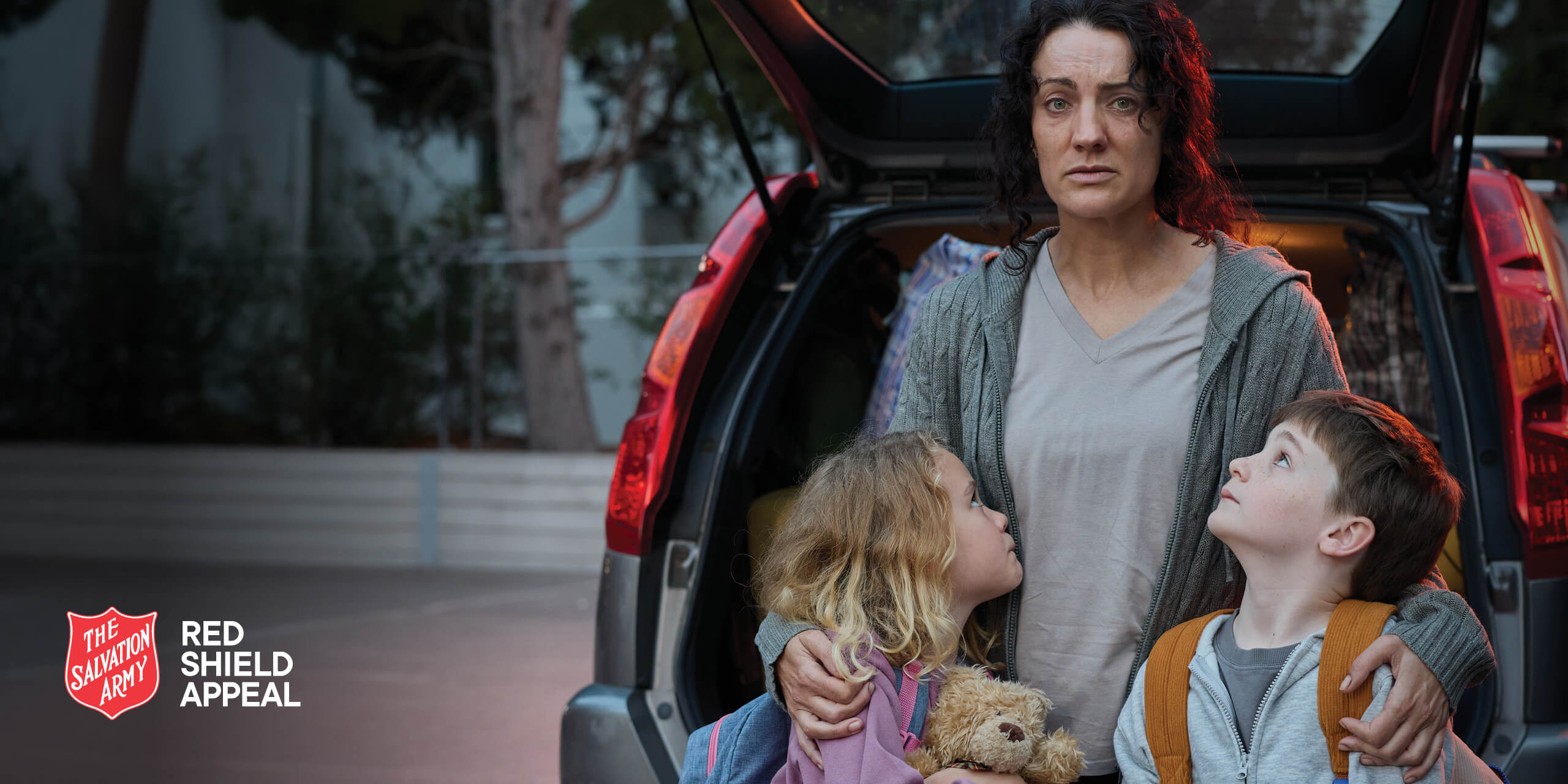 Suzi looking distressed with her two children at the boot of her car.
