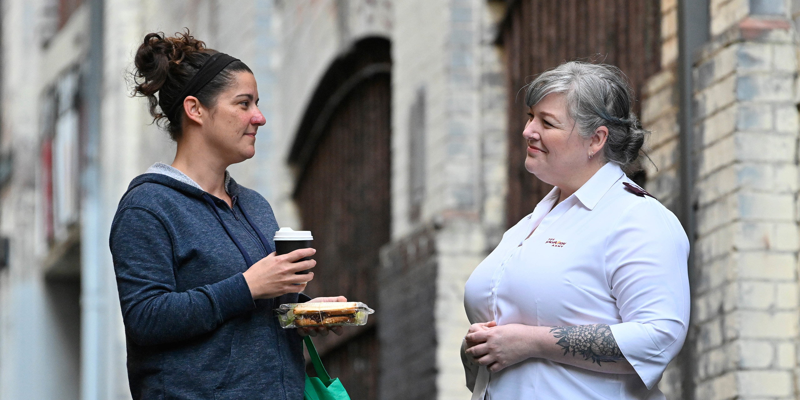 A Salvo chatting with a woman with a hot drink in the street