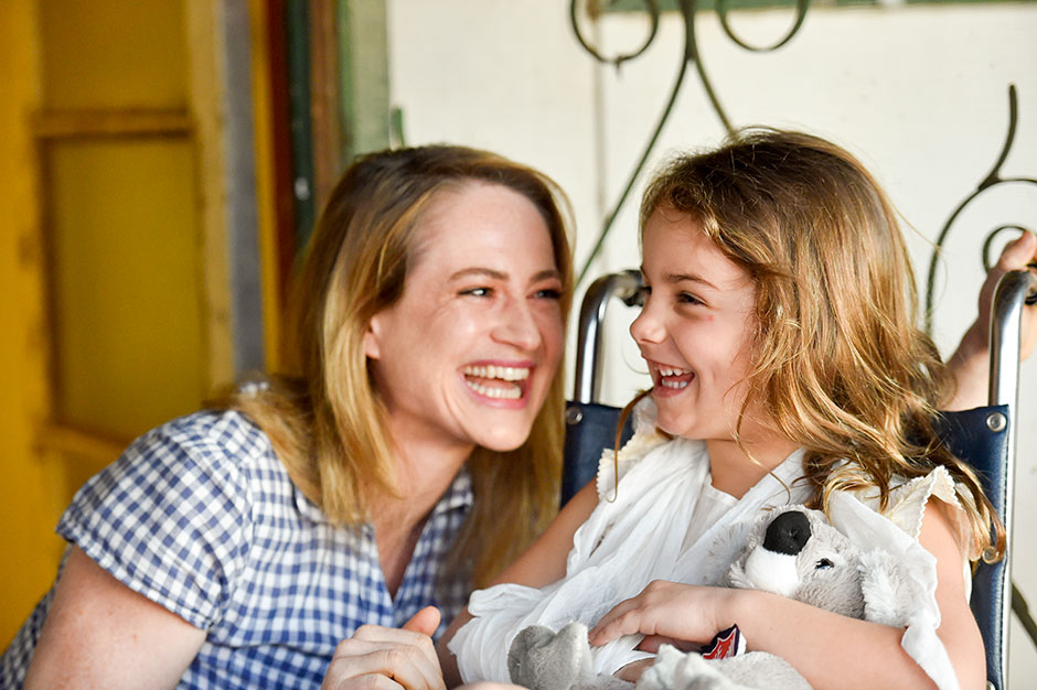 A smiling child holding a gift in a wheelchair
