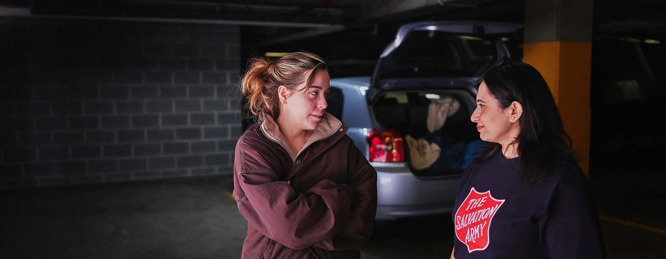 A young woman talks with a Salvos volunteer beside her car.