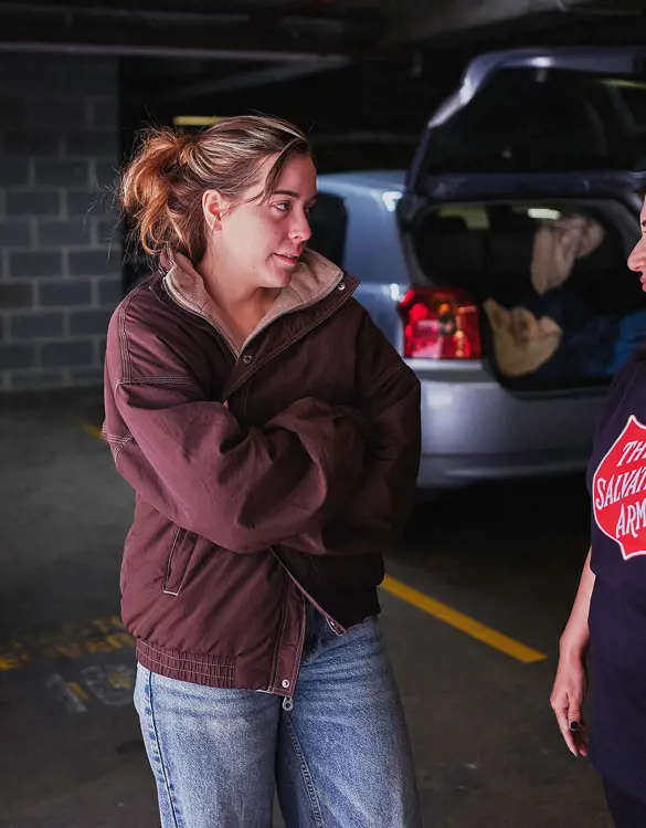 A young woman talks with a Salvos volunteer beside her car.