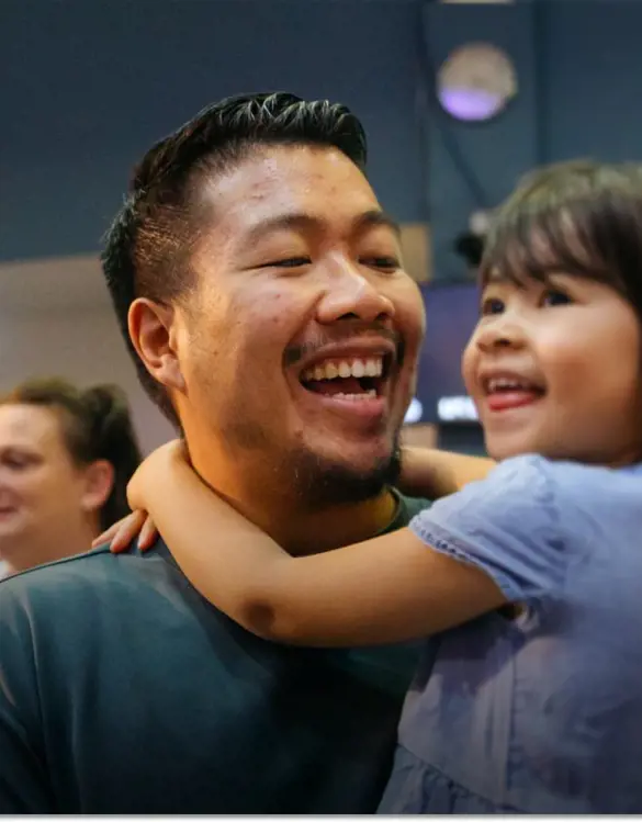 Two parents hold their young children as they all sing during a Sunday service.