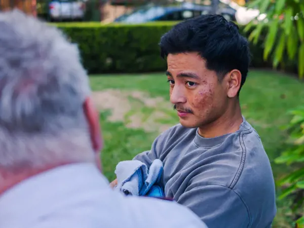 A young man talks with a Salvos officer in a park.