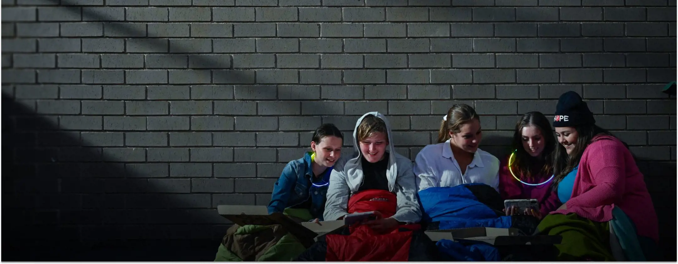 Five girls huddle happily in warm clothes and sleeping bags.