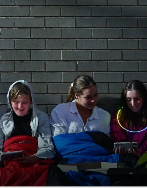 Five girls huddle happily in warm clothes and sleeping bags.
