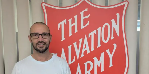 Natham standing in front of The Salvation Army shield logo.