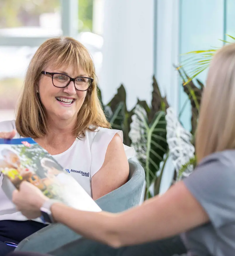 Two women sit discussing a Wills brochure that one holds.