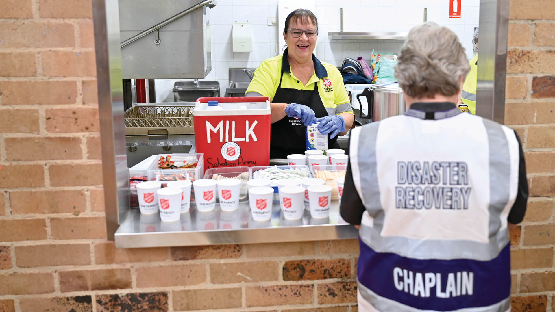 An emergency service Salvos volunteer doles out tea and coffee from a canteen window.