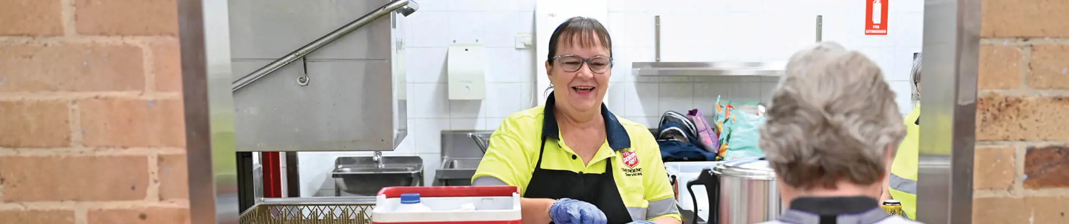 An emergency service Salvos volunteer doles out tea and coffee from a canteen window.