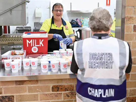 An emergency service Salvos volunteer doles out tea and coffee from a canteen window.