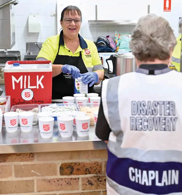 An emergency service Salvos volunteer doles out tea and coffee from a canteen window.