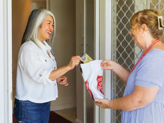 A Salvos doorknock volunteer gratefully accepts another donation.