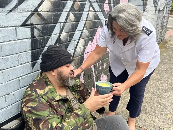 Salvos officer helping someone on the street.