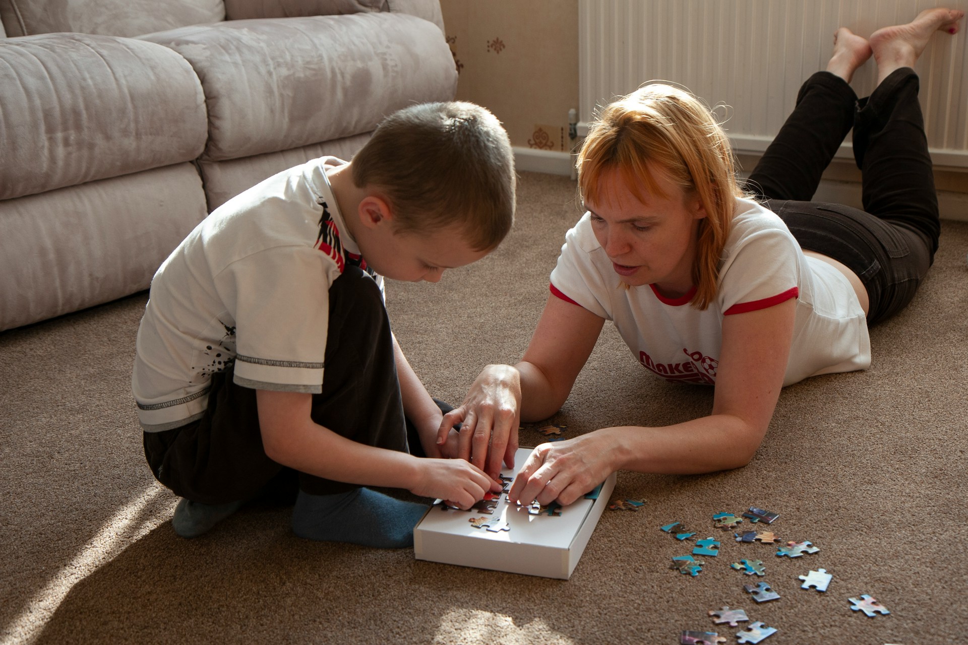 Parent and child playing with a puzzle on the floor