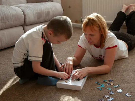 Parent and child playing with a puzzle on the floor