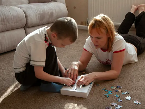 Parent and child playing with a puzzle on the floor