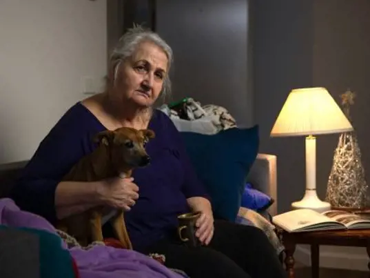 An older woman seems disconsolate as she sits with her small dog.