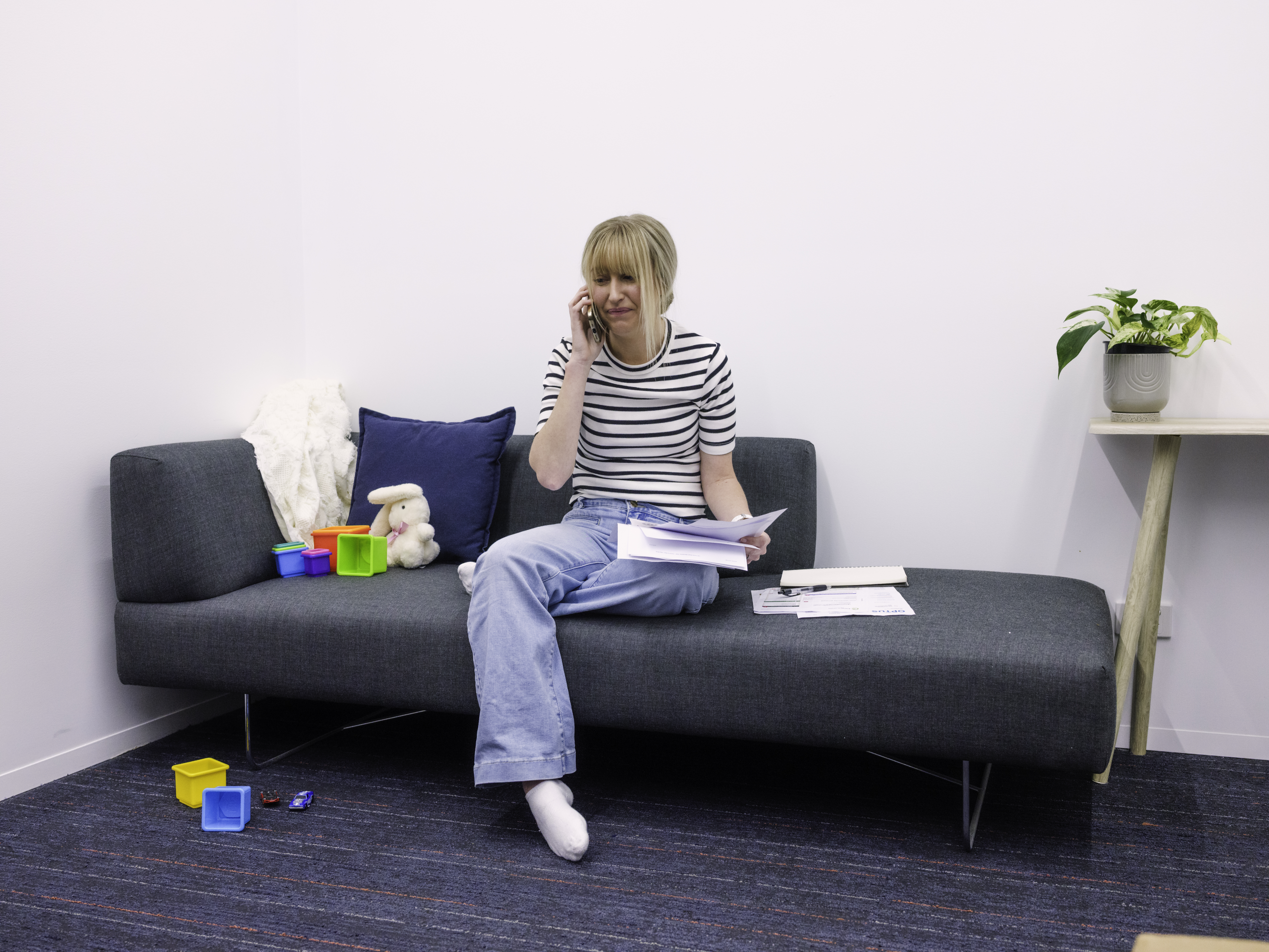A woman appears to be stressed, holding a handful of bills as she talks on the phone.