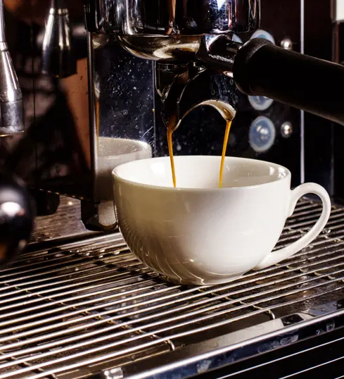 Coffee being poured from a coffee machine into a cup.