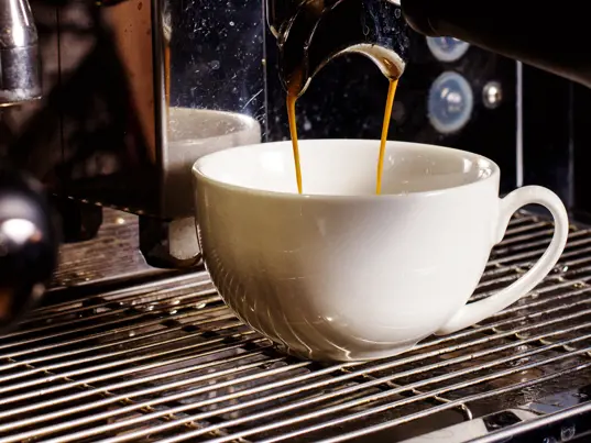 Coffee being poured from a coffee machine into a cup.