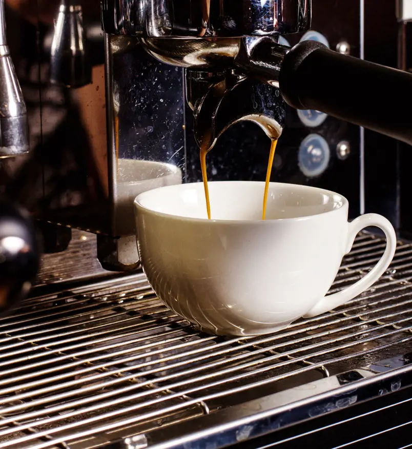 Coffee being poured from a coffee machine into a cup.