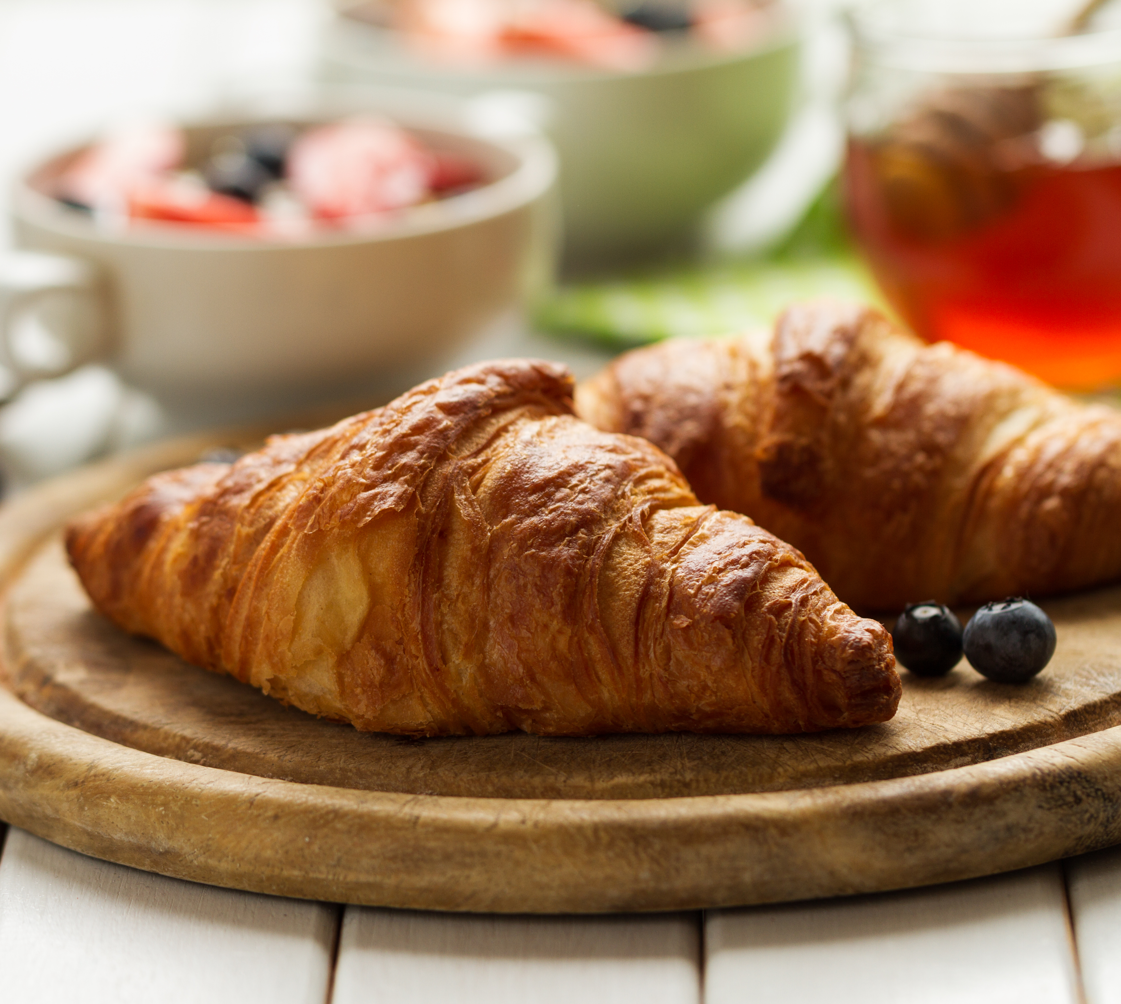 Croissants on a wooden plate with some fresh blueberries.