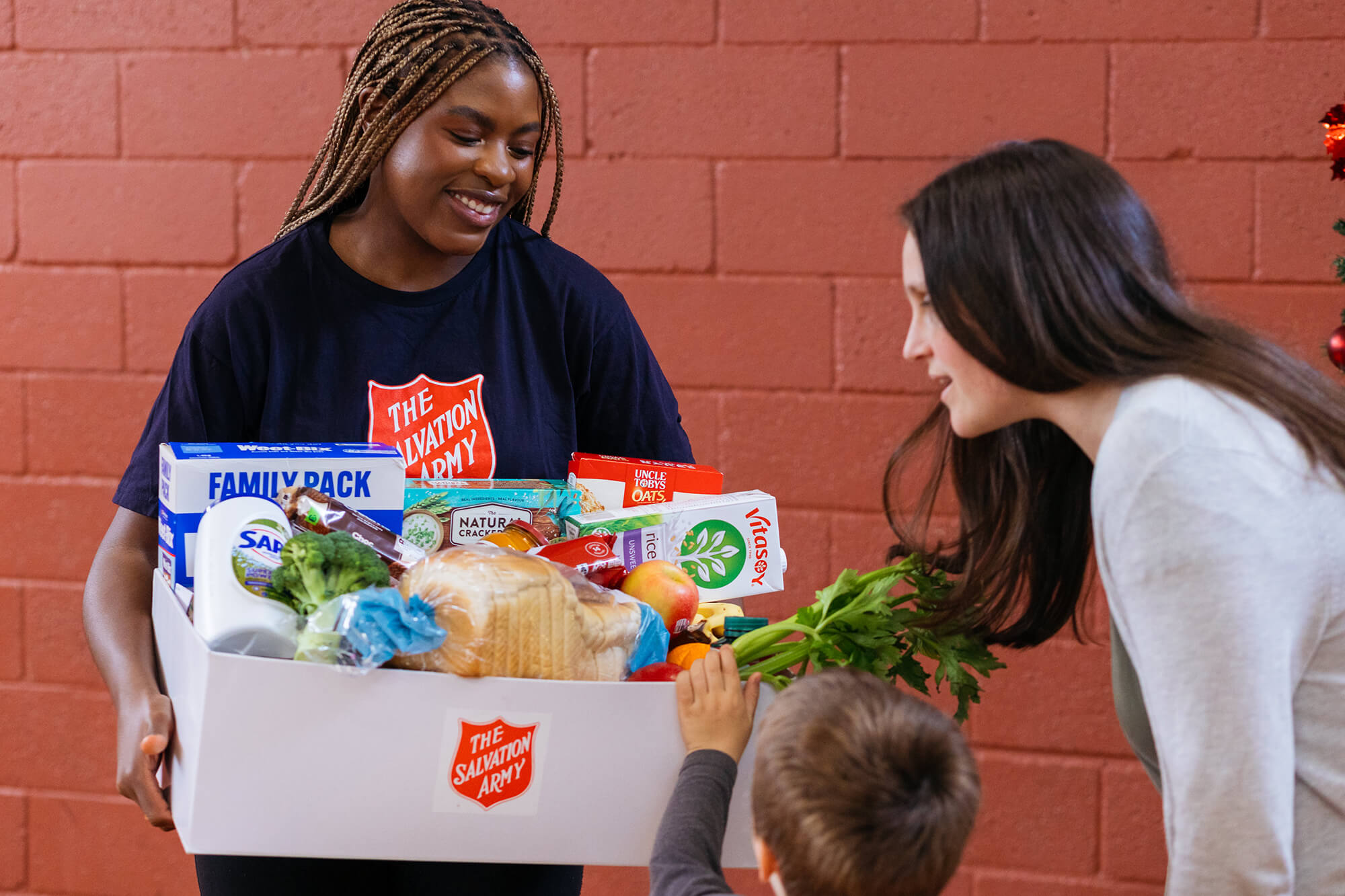 Salvos team member handing our grocery essentials to a family