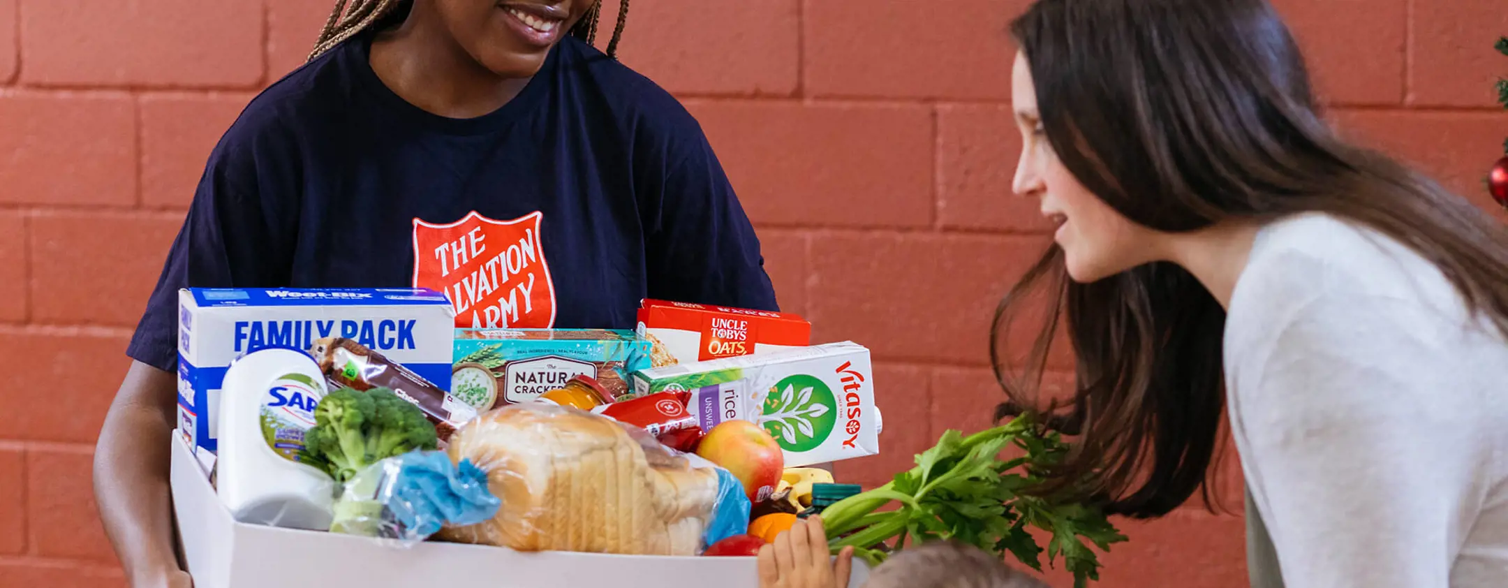 Salvos team member handing our grocery essentials to a family