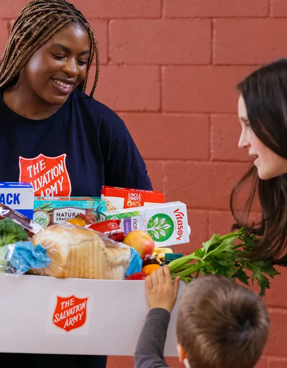 Salvos team member handing our grocery essentials to a family