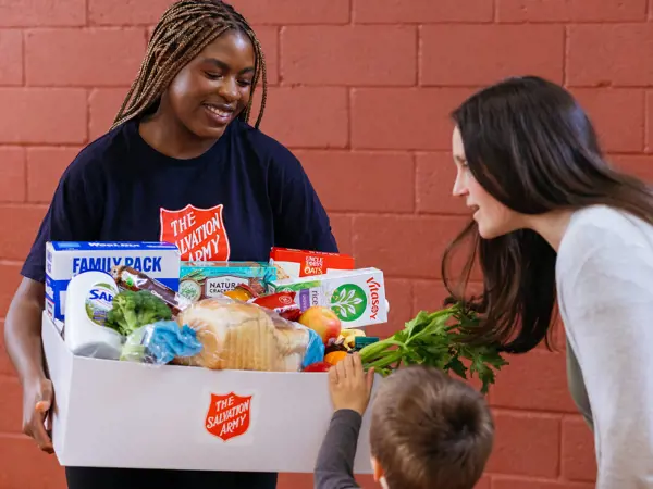 Salvos team member handing our grocery essentials to a family