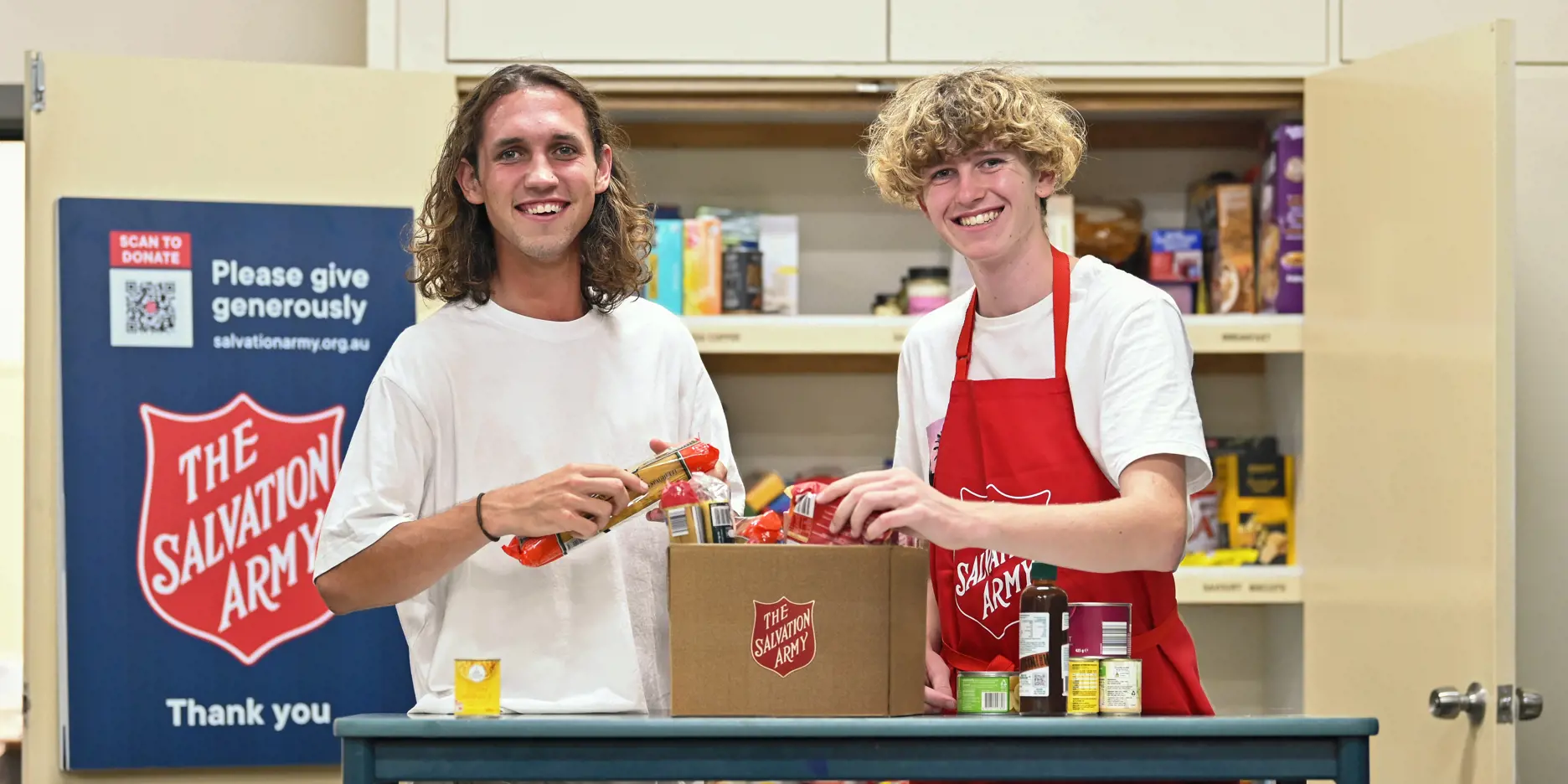 Two young people preparing food hampers for the community.