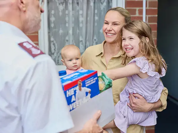 An officer delivers a box of groceries to a young mother.